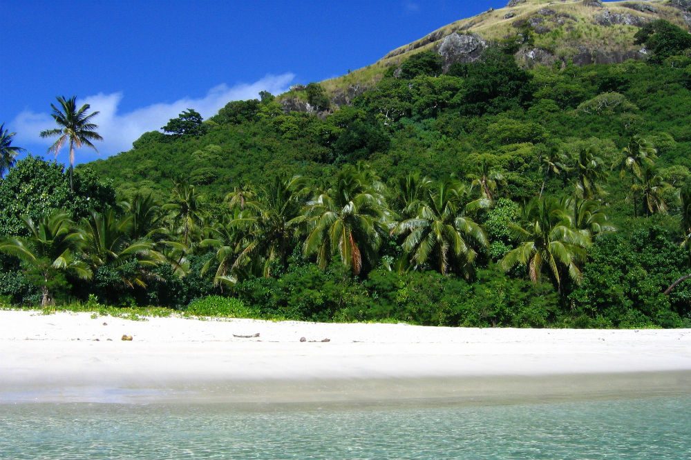 green mountain and beach with clear water on Mamanuca island Fiji