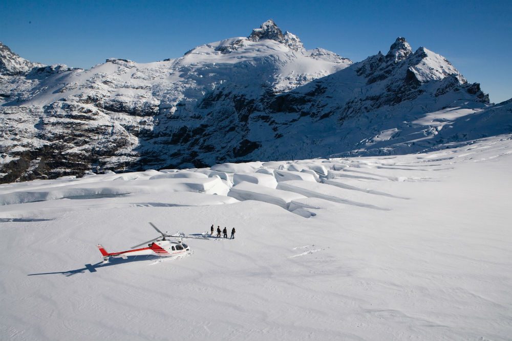 snow covered Clarke Glacier, Queenstown, New Zealand with a red helicopter on it