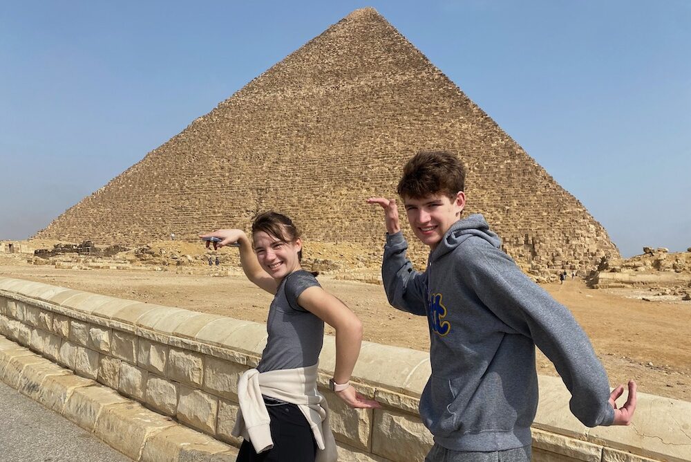 Travelers posing in front of one of Giza pyramids