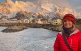 Brook in Norway in winter, posing at the Lofoten Islands, with snowy mountains, the Norwegian Sea and houses in the background.