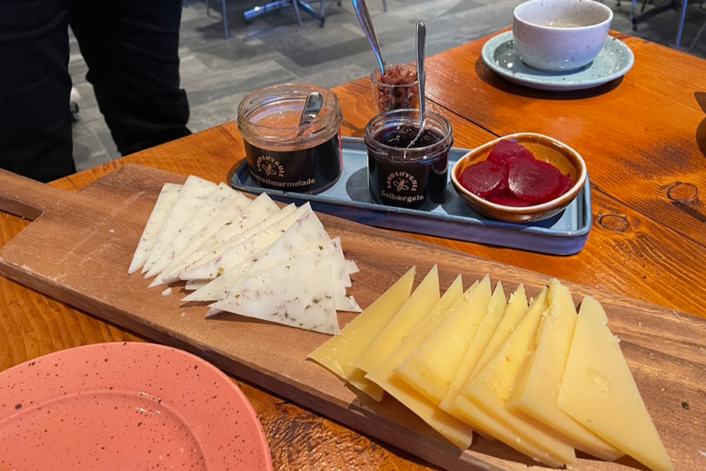 Artisanal cheeses cut on a wooden board with beets, and other jams on the side.