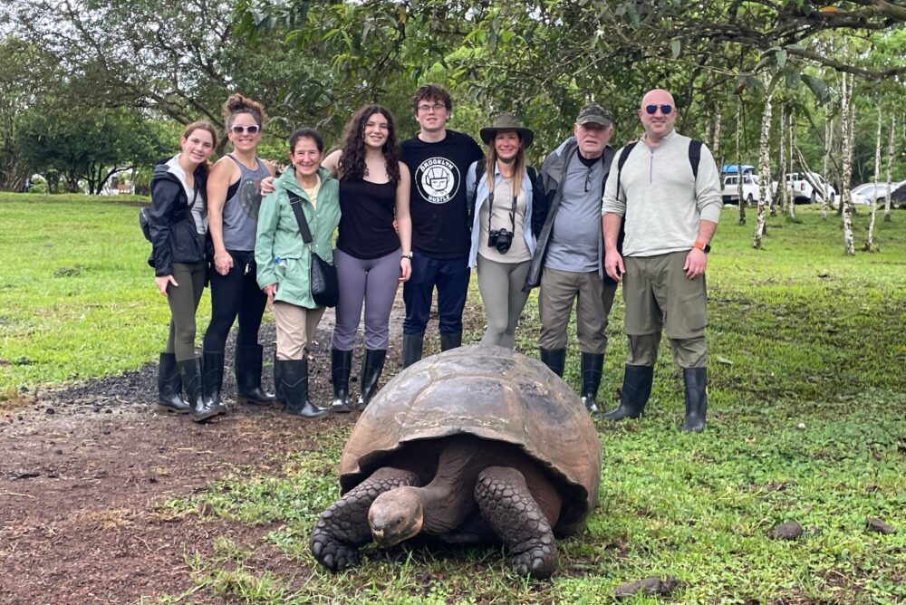 Travelers and a giant tortoise in the Galapagos.