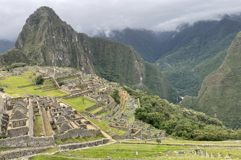 Machu Picchu on a cloudy day with mountains in the background.