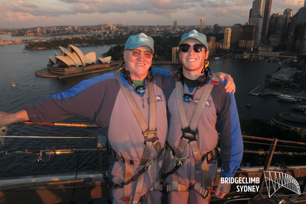 Two travelers climbing the Sydney Harbour Bridge climb.