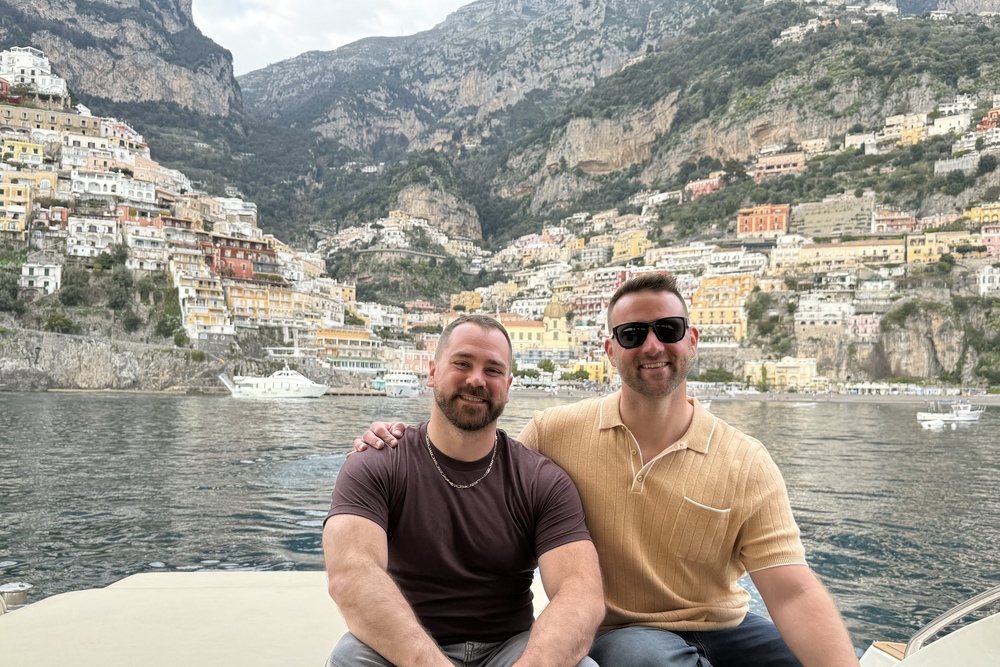 Travelers Dan Gorbett and husband Mike Wellner on a private yacht exploring the Amalfi Coast with Positano in the background, Italy.
