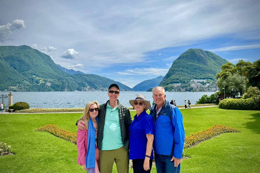 Travelers taking a group shot beside Lake Lugano in Switzerland.