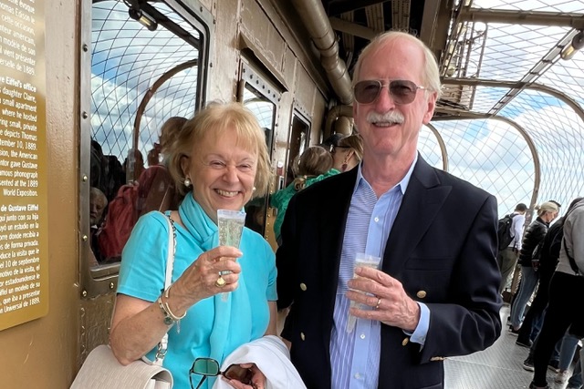 Travelers Sonja Haggert and her husband toasting atop the Eiffel Tower, Paris.