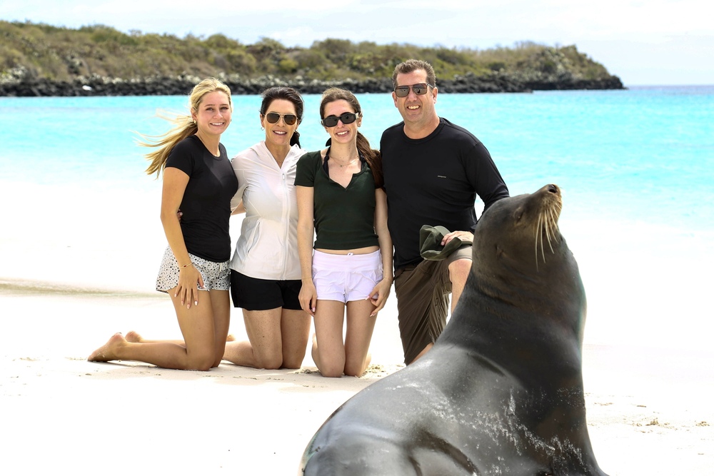 Travelers Claire, Andrea, Rachel and Dave Phillips bonding with sea lions at Gardner Bay on Espanola Island, Galapagos.