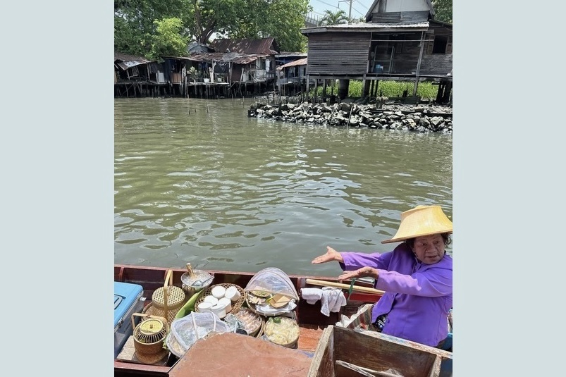 A woman on a boat delivers Thai snacks to April Milford and her family on their WOW Moment in Bangkok, Thailand.
