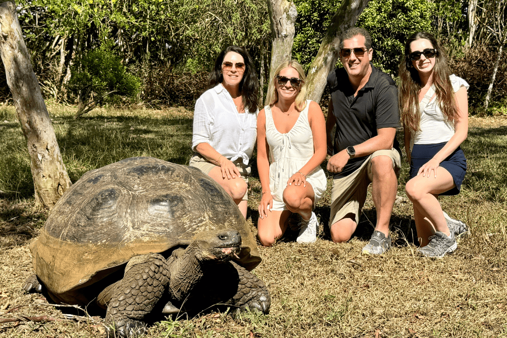 Traveler Andrea Phillips and family next to a giant tortoise in the Galapagos Islands, Ecuador.