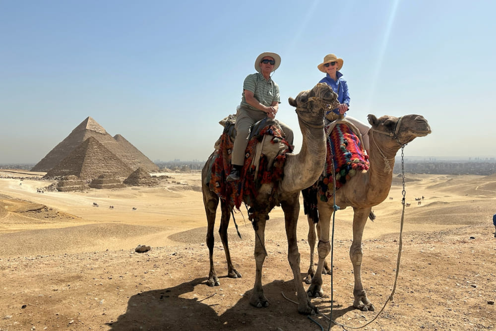 Travelers Jeff and Linda Stengel on camels, near Giza pyramids in Cairo, Egypt.