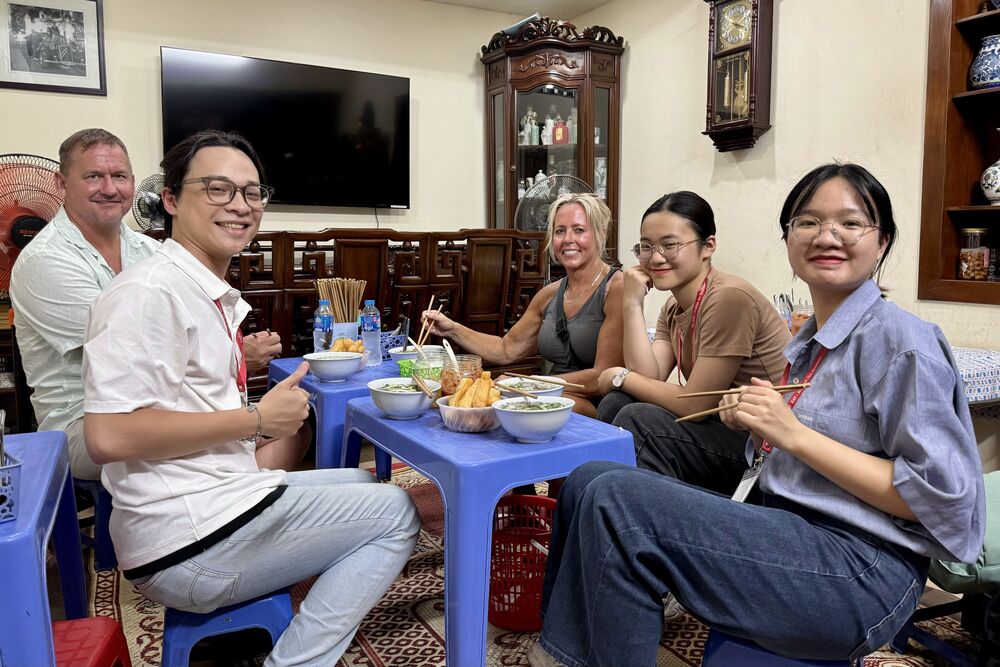 Travelers Mark and Sandra Questad learn how to eat pho in a private home with their guides in Hanoi, Vietnam.