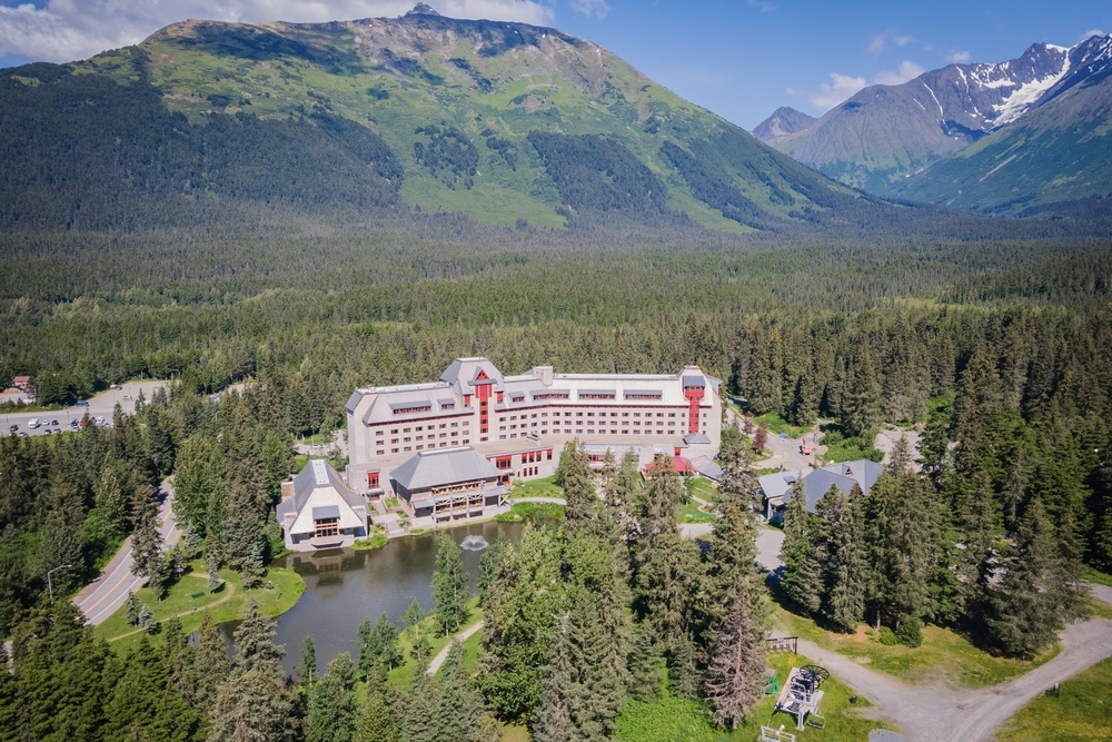 Drone shot of Alyeska Resort surrounded by trees and mountains during summer, Alaska.