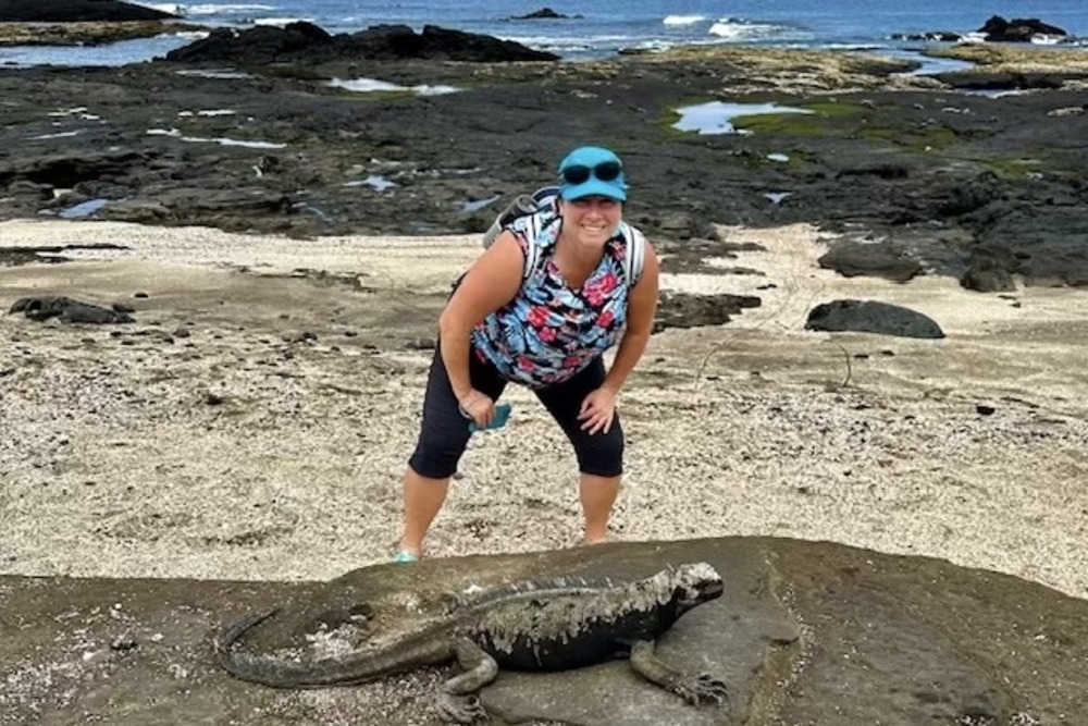 Judy Calvert next to an iguana in Galapagos Islands, Ecuador.