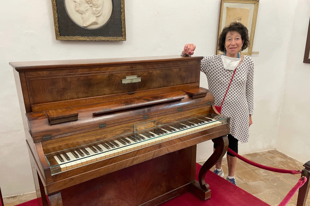 Mina Miller Sabritt next to a piano in the Chopin Museum, in Mallorca.