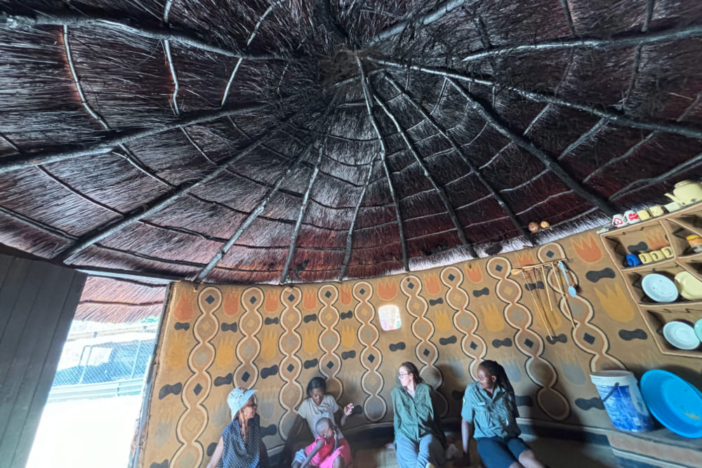 Sara Edwards visiting a woman and her granddaughter in their hut, in Zimbabwe, Africa.