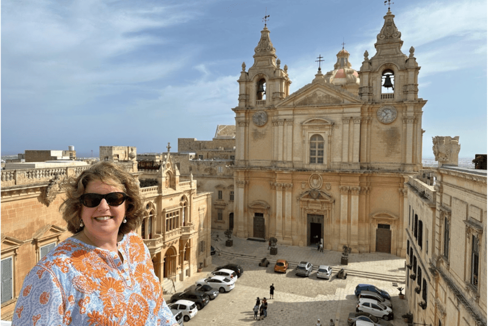 Wendy Perrin with a medieval church in the background, in Malta.