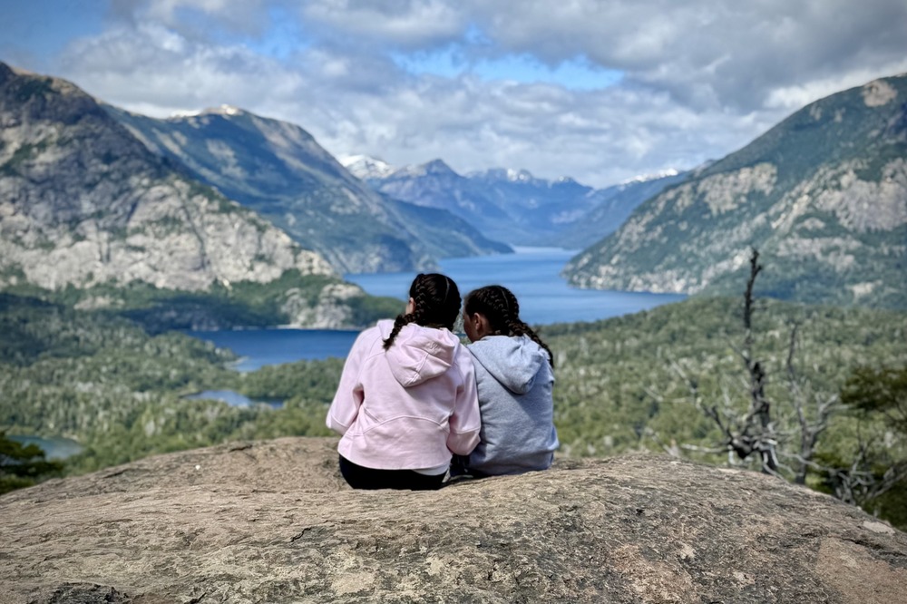 Two girls sitting and overlooking mountains in Bariloche, Patagonia.